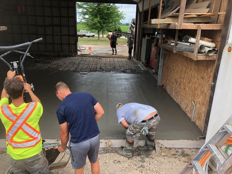 Workers finishing a newly placed concrete floor inside a building
